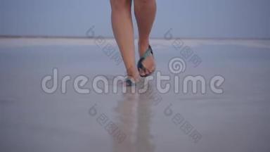 日落时分，穿着绿色凉鞋的女孩在盐湖的<strong>水洼</strong>中飞溅